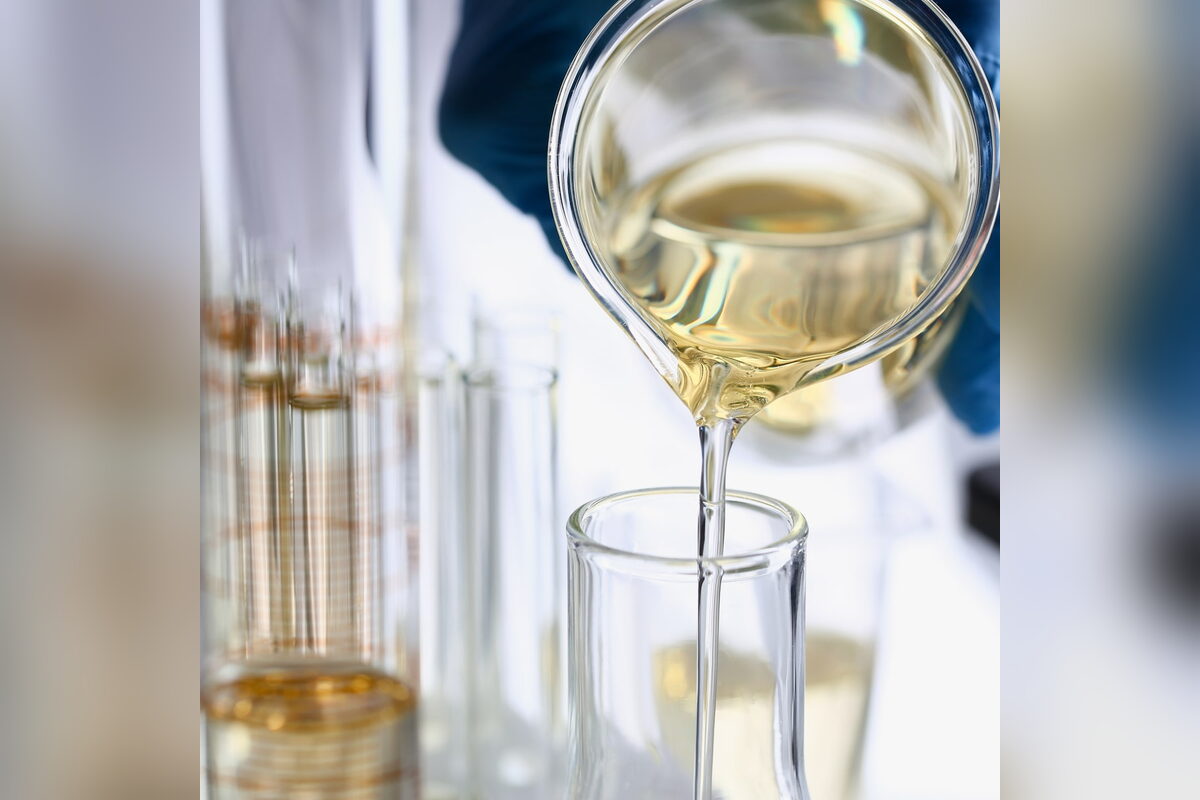 Pale yellow liquid being poured between lab beakers