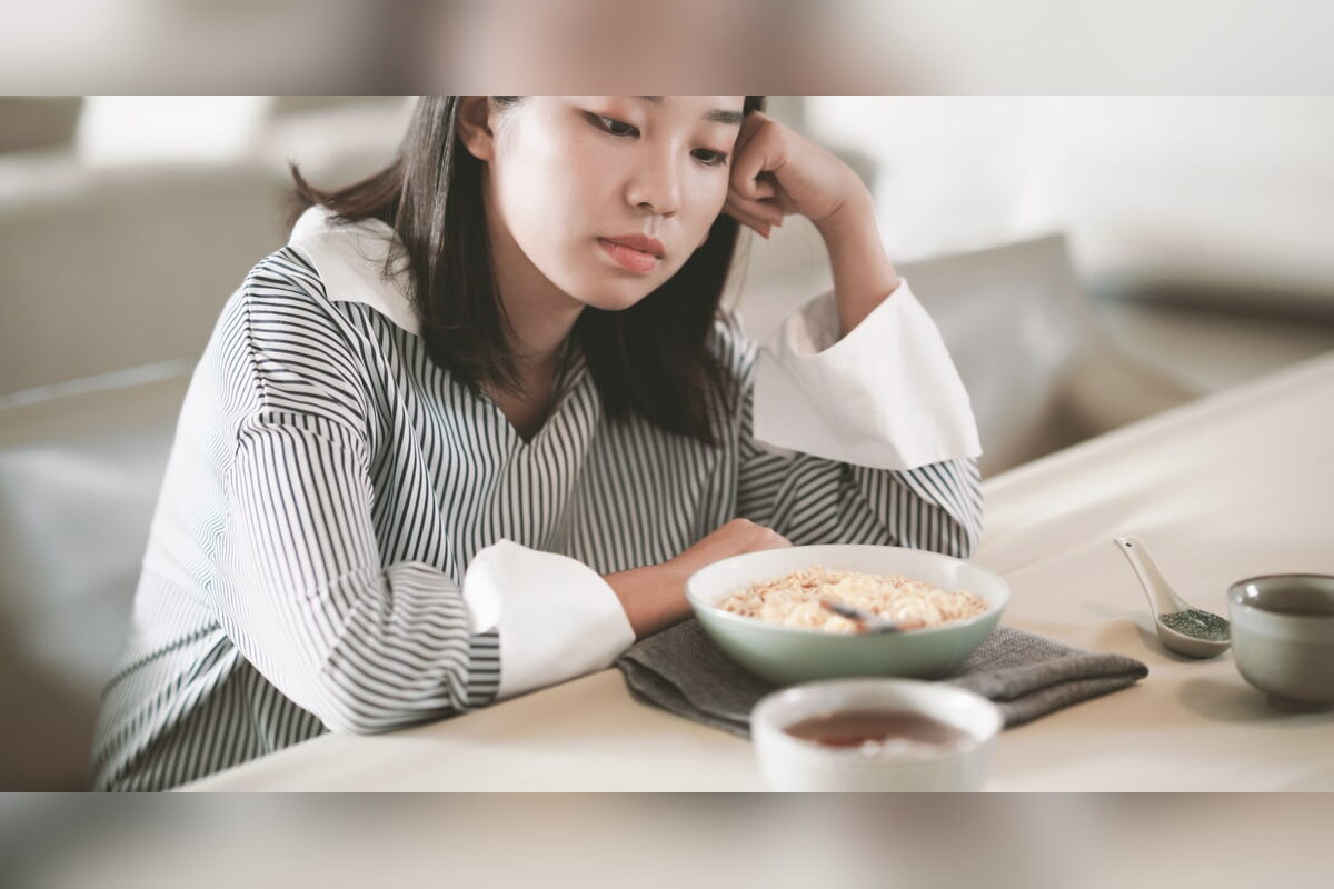Tired woman resting her head on her hand at a breakfast table