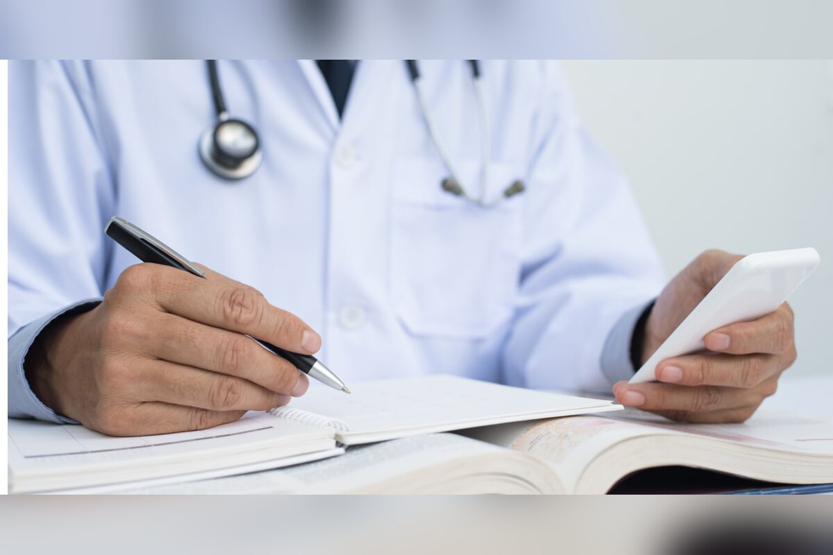 Doctor writing research notes while checking a phone