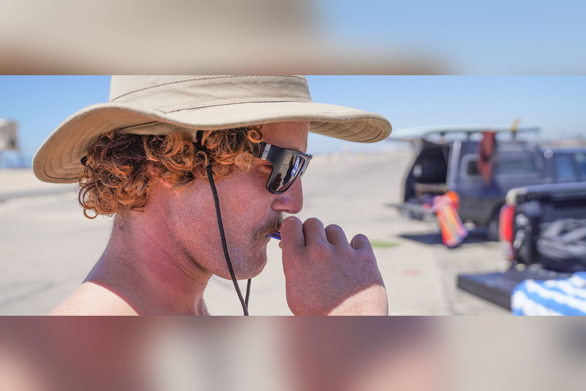 Man in a sun hat vaping on a beach parking lot