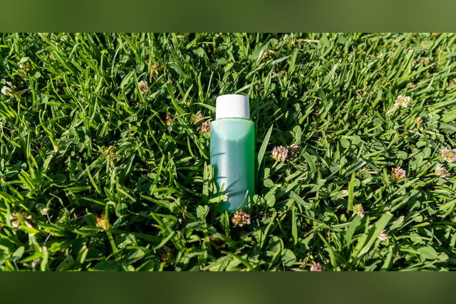 Green Omni Cleansing Shampoo bottle standing in the grass
