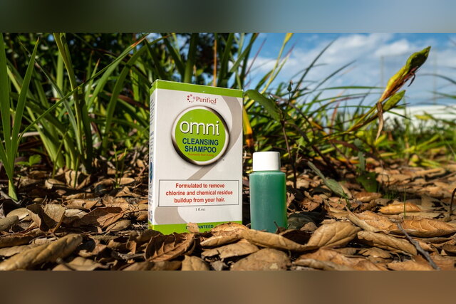 Omni Cleansing Shampoo box and green bottle on the ground
