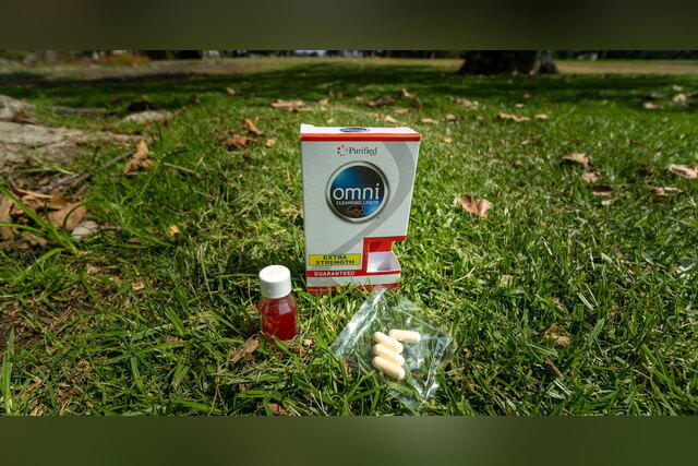 Omni Cleansing Liquid box, bottle and capsules on the grass