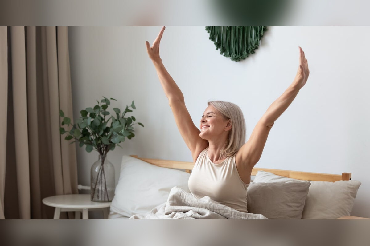 Happy woman stretching her arms in bed after waking up