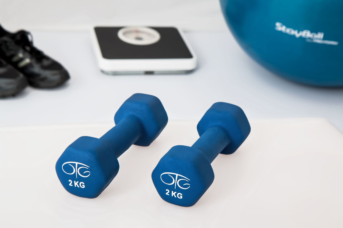 Blue dumbbells, a bathroom scale and sneakers for exercise