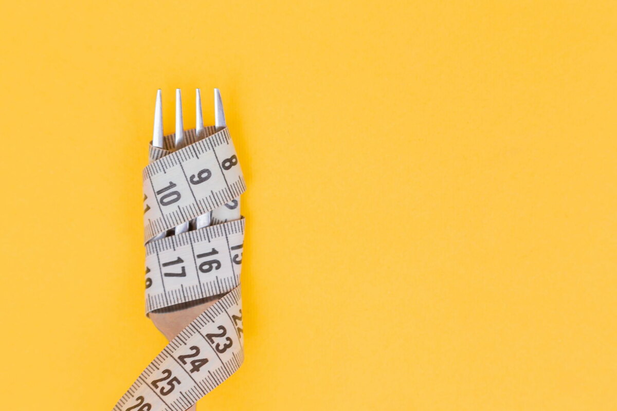 Measuring tape wrapped around a fork on a yellow background