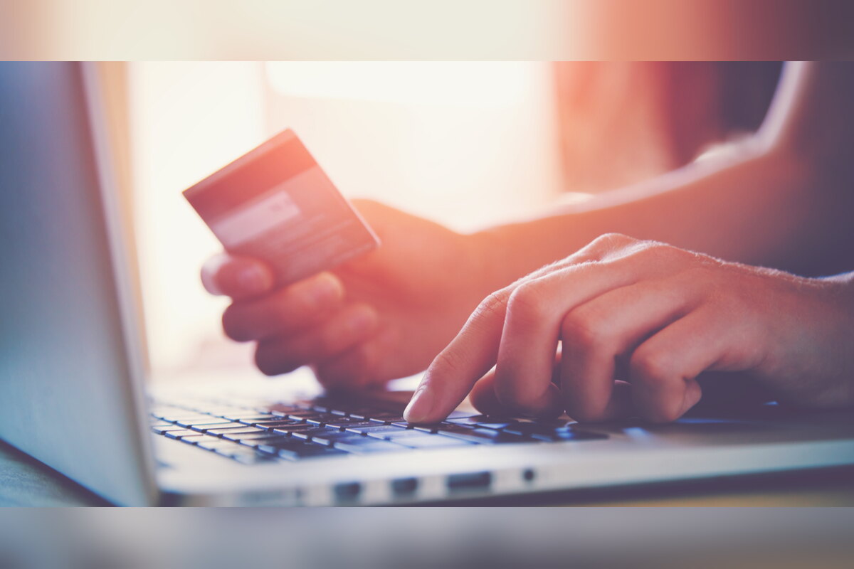 Hands holding a credit card while typing on a laptop