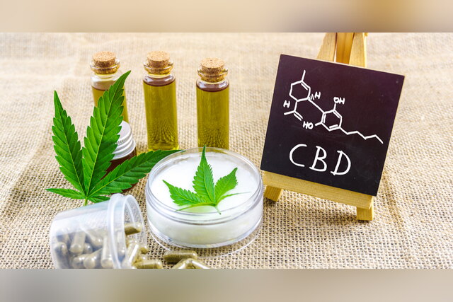 CBD oil vials, cream and capsules next to a "CBD" chalkboard