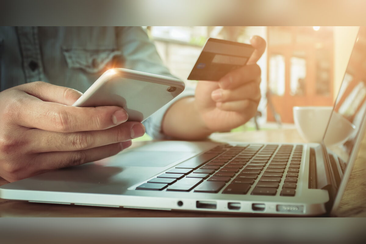 Person paying online with a credit card, phone and laptop